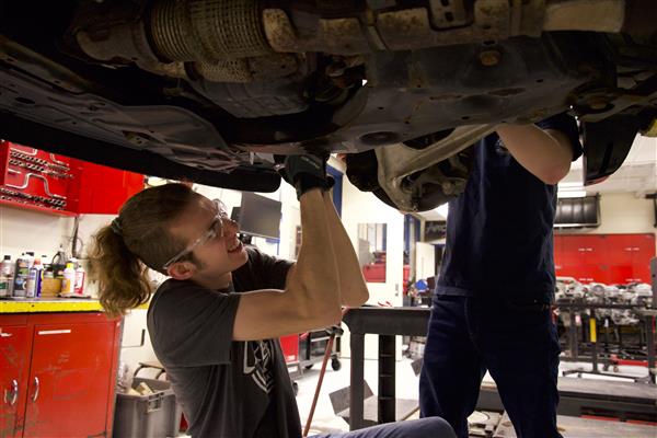 Students work on the undercarriage of an elevated car in their automotive class of Hoffman Estates High School.